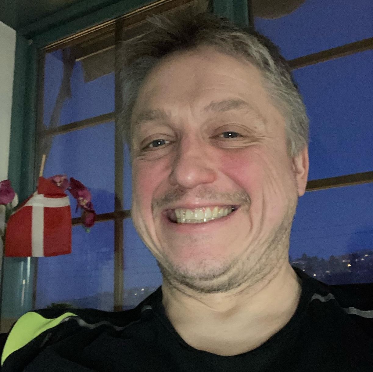 Smilende mann i mørk genser