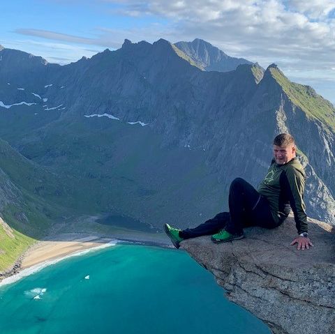 Mann sitter på toppen av fjell